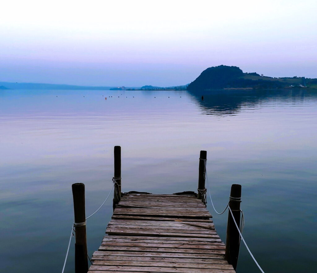 Foto di ponticello sul lago di Bolsena con piccolo promontorio sullo sfondo.