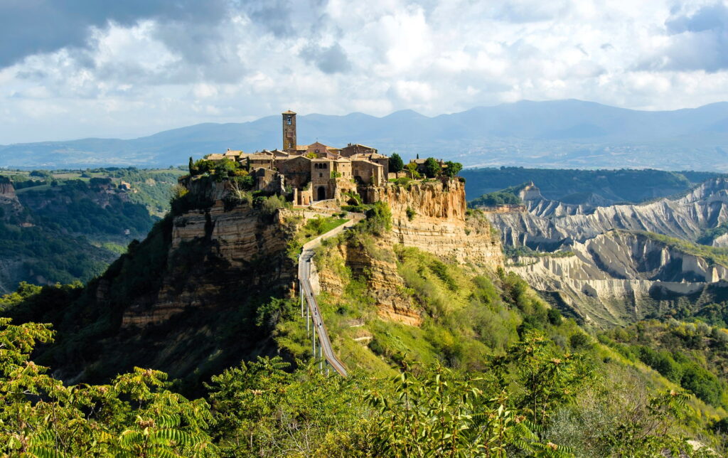 Veduta di Civita di Bagnoregio con ponte e paesaggio intorno.