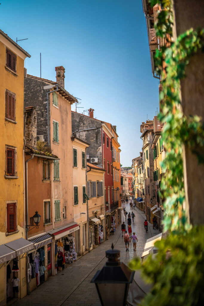 Veduta del centro di Rovigno dall'alto con case colorate, negozi e persone.