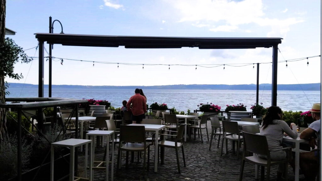 Veduta di un bar all'aperto con persone sul lungolago di Trevignano Romano, nel Lazio.