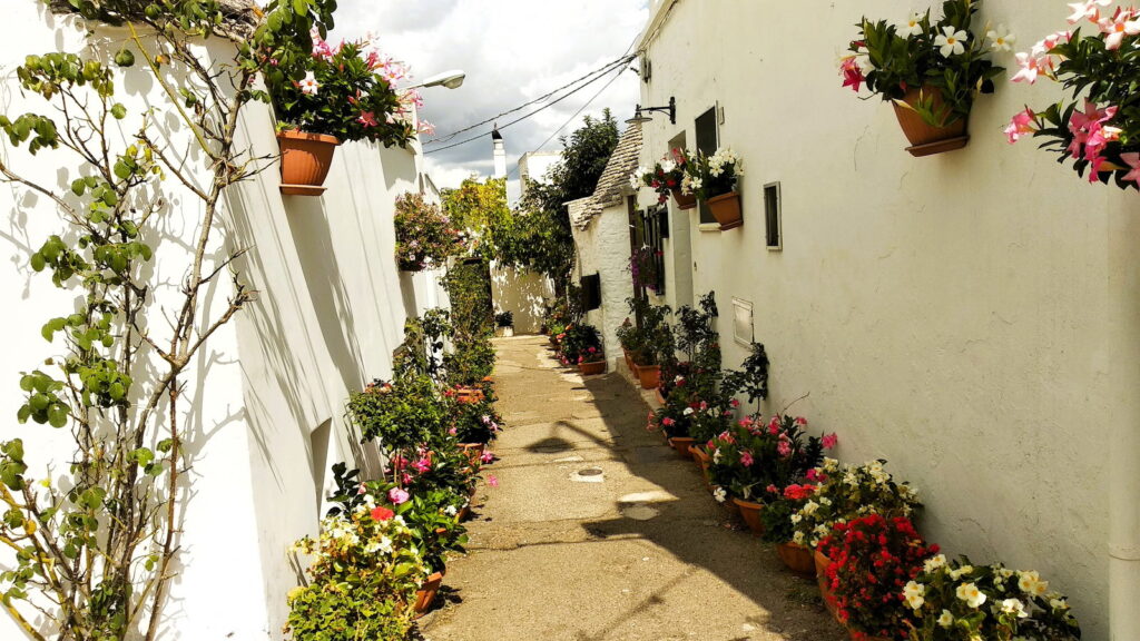 Vicolo con vasi di fiori e trulli ad Alberobello, in Puglia