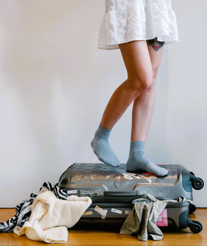 Ragazza in piedi su valigia che non si chiude.