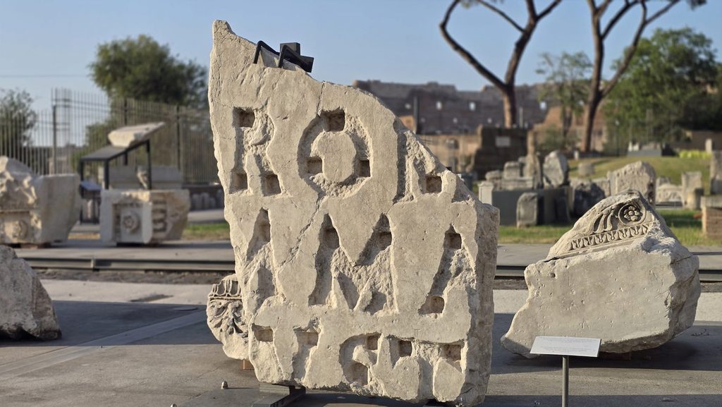 Frammento con iscrizione nel Parco Archeologico del Celio e Colosseo sullo sfondo